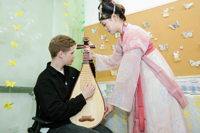 留学生体验如何弹奏中国古典乐器琵琶。校方供图