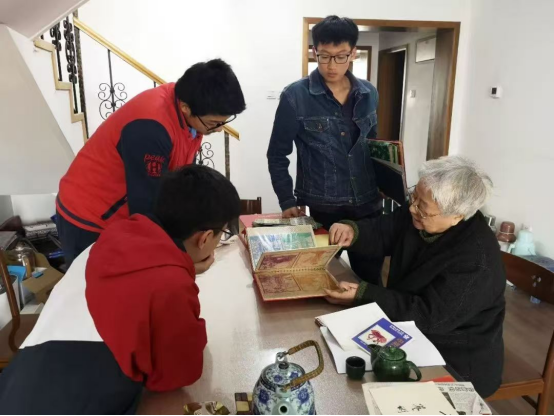 2019年，岳同给来家看望的志愿者们展示收藏的剪纸、中国画作品。中国人民大学供图